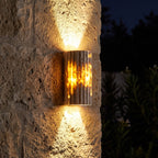 Compact Yellow Travertine Up Down Outdoor Wall Light glowing on a garden wall at night