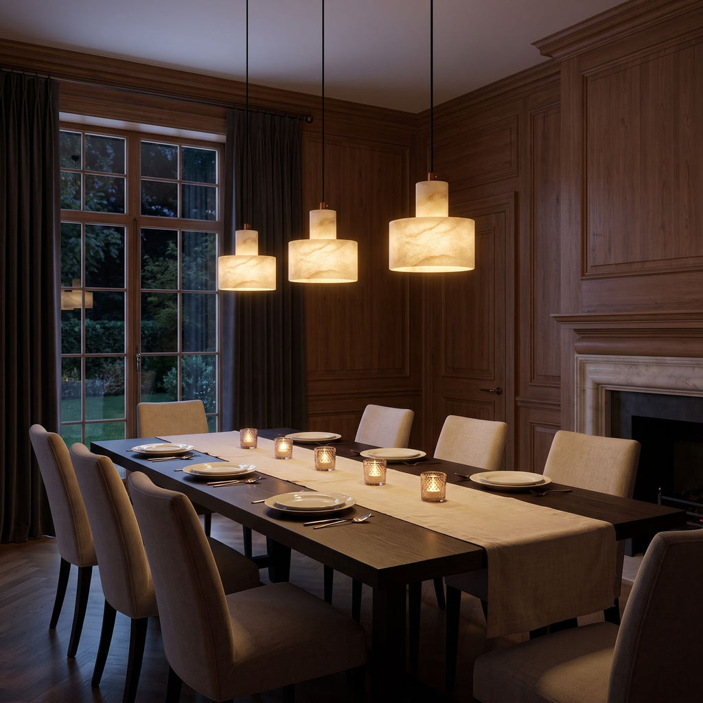 Row of three Copper and Alabaster Cylinder Pendant Lights above a long dining table in a classic dining room at night