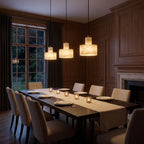 Row of three Copper and Alabaster Cylinder Pendant Lights above a long dining table in a classic dining room at night