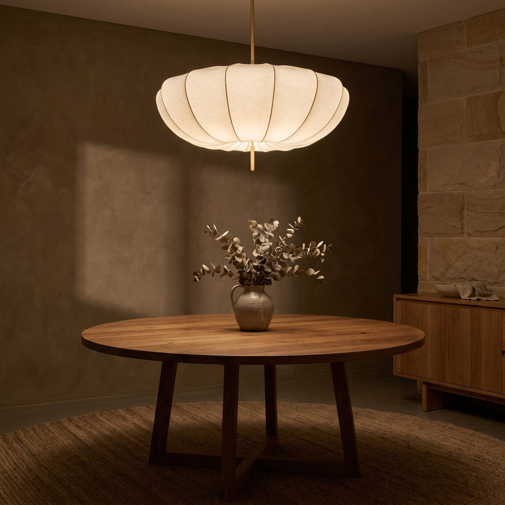 Cream Fabric Wabi Sabi Pendant Light glowing against a plaster wall at night
