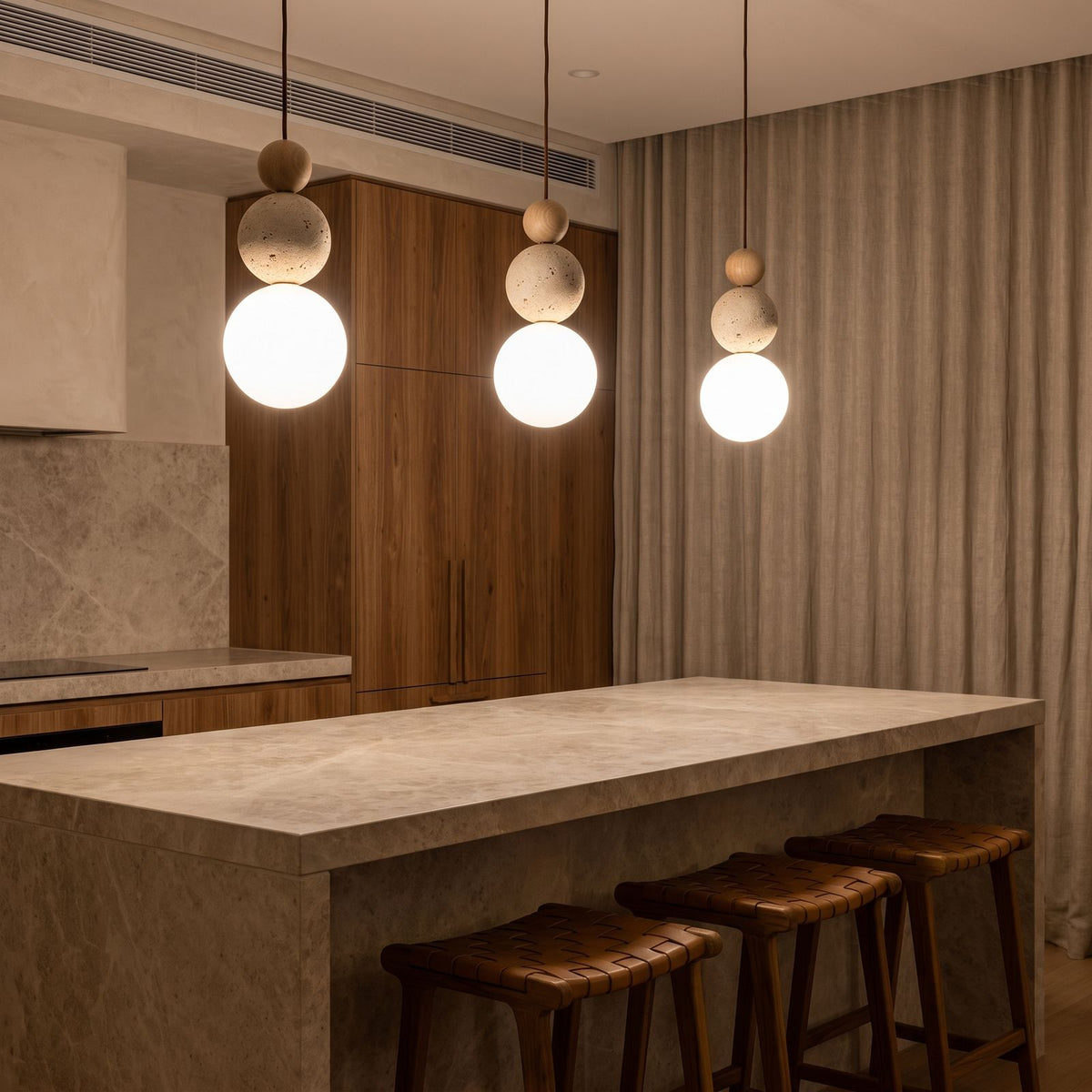 A row of three Cream Stone Ball Bedside Pendant Lights over a stone kitchen island