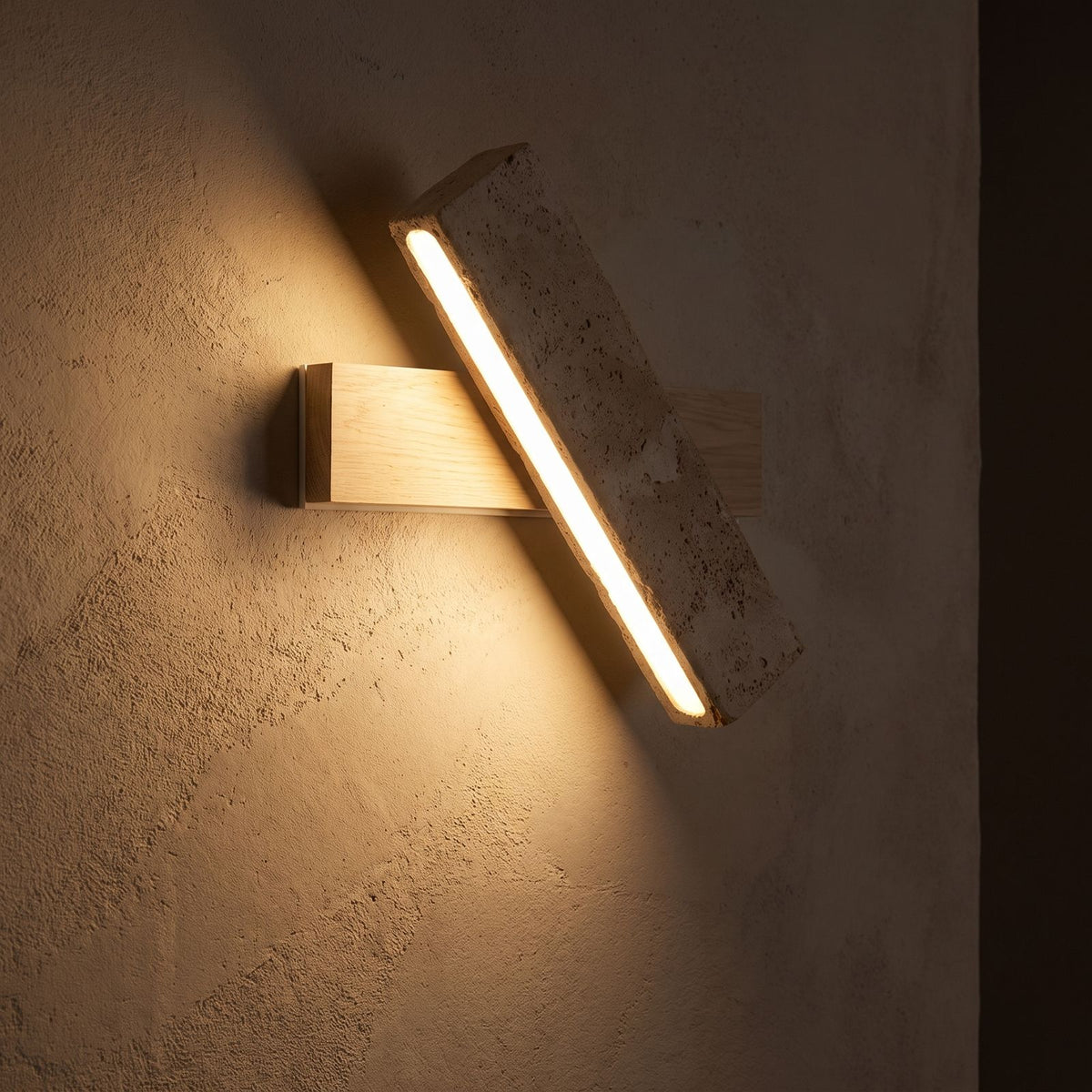 Crossed Travertine and Wood Rotating Wall Light glowing on a plaster wall at night