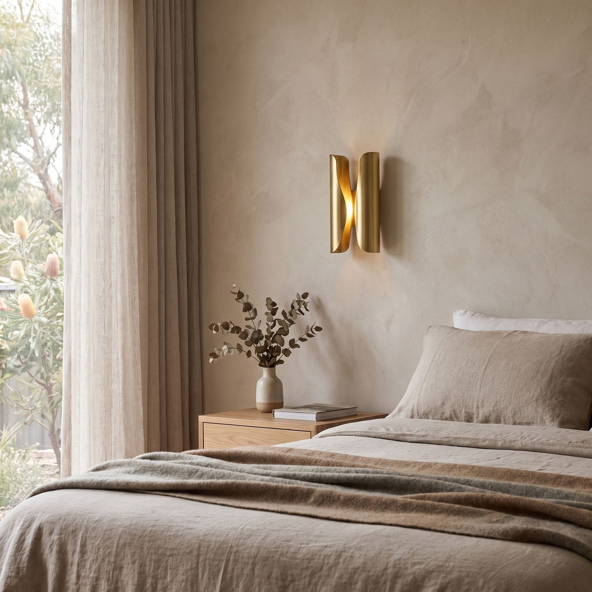 Curled Brass Panel Wall Sconce on a bedroom wall beside the bed