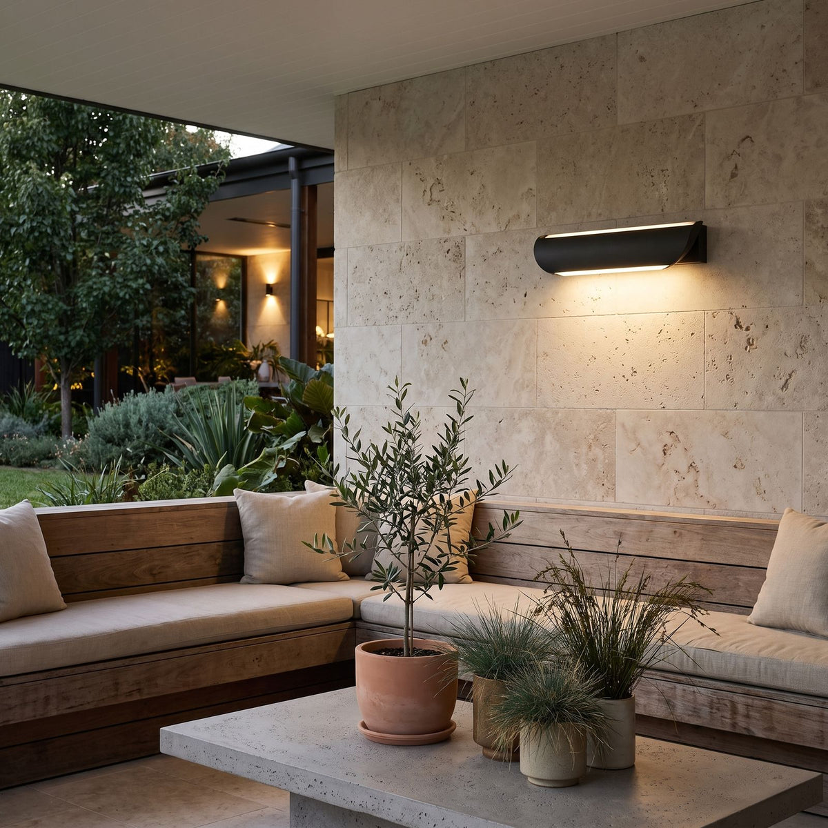 Curved Acrylic LED Outdoor Wall Light on a travertine wall in a covered outdoor lounge