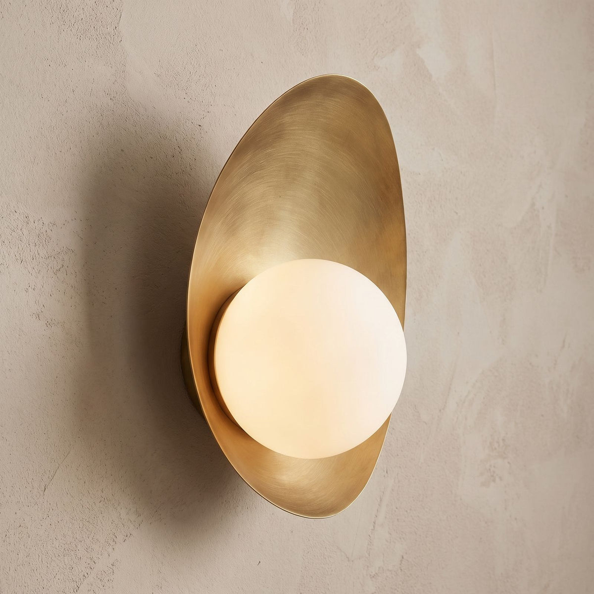 Curved Gold Shield Opal Globe Wall Light, close view at 45 degrees on a plaster wall