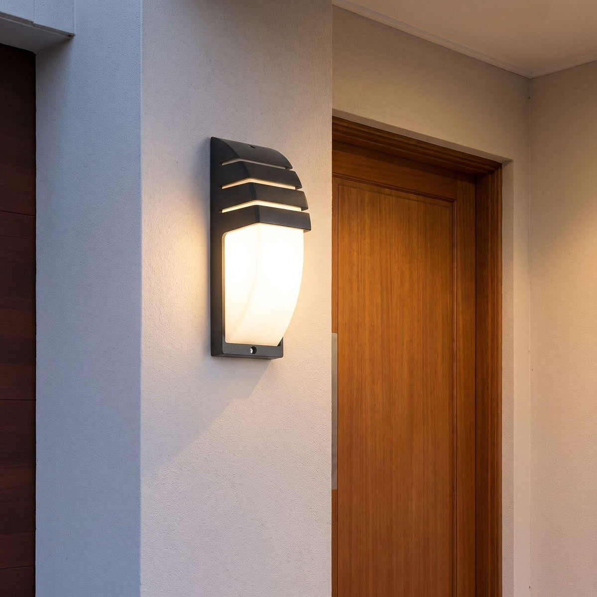 Curved Louvred Aluminium Sensor Outdoor Wall Light beside a timber front door at dusk