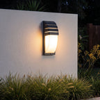 Curved louvred sensor outdoor wall light on a garden wall at night