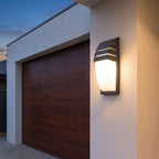 Curved louvred sensor outdoor wall light beside a garage door at dusk