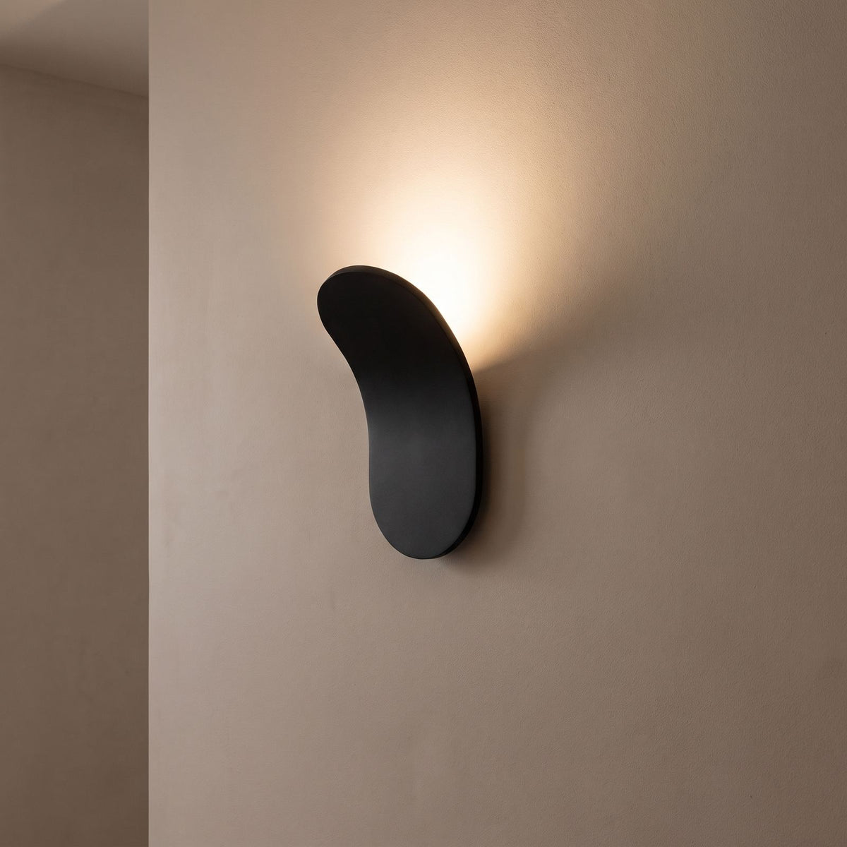 Curved metal paddle indirect wall light on a hallway wall