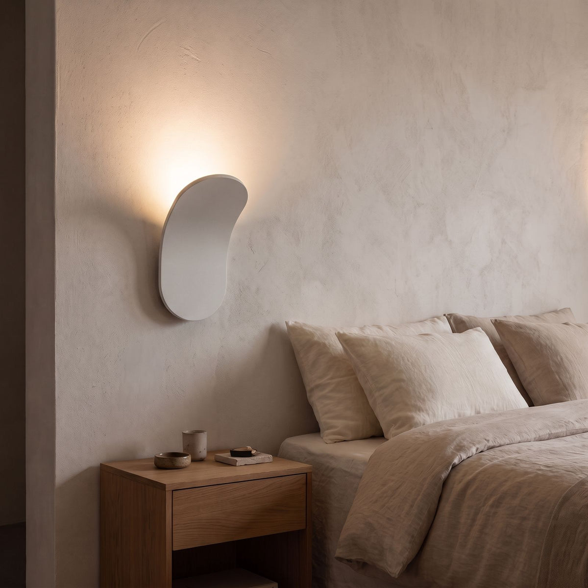 Curved Metal Paddle Indirect LED Wall Light in white beside a bed