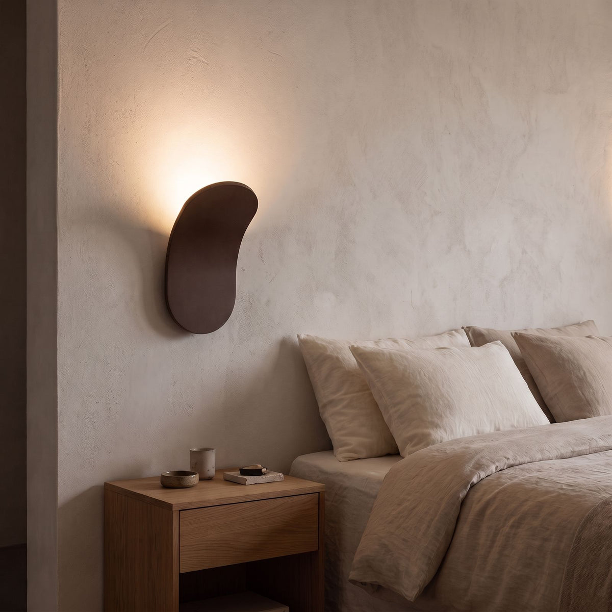Curved Metal Paddle Indirect LED Wall Light in brown beside a bed