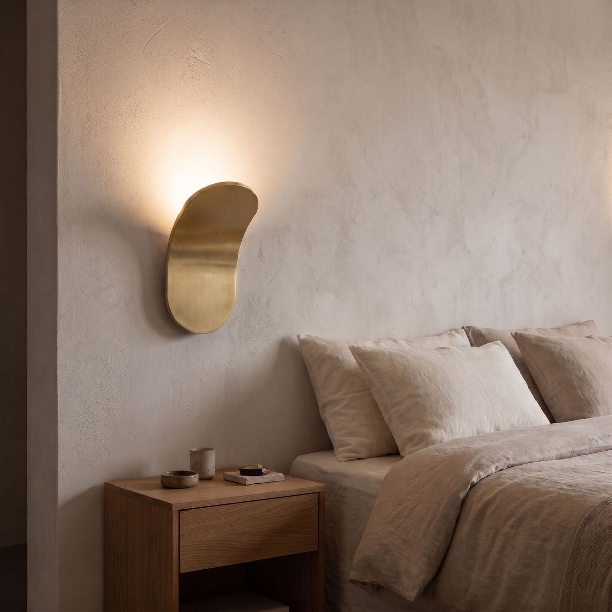Curved Metal Paddle Indirect LED Wall Light in gold beside a bed