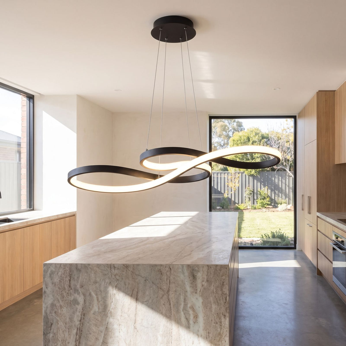 Curved ribbon aluminium LED pendant light over a kitchen island in daylight