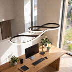 Curved ribbon aluminium LED pendant light above a home office desk in daylight