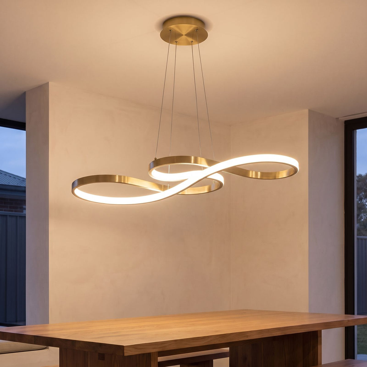 Curved Ribbon Aluminium LED Pendant Light in gold above a dining table