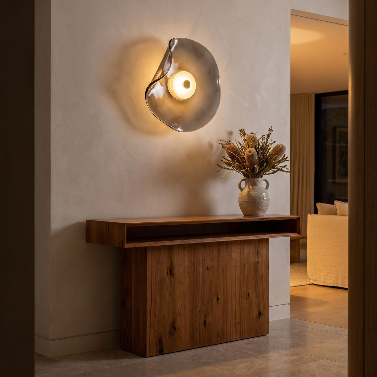 Curved Smoke Glass Up Down Wall Light above a timber console in an entry hallway