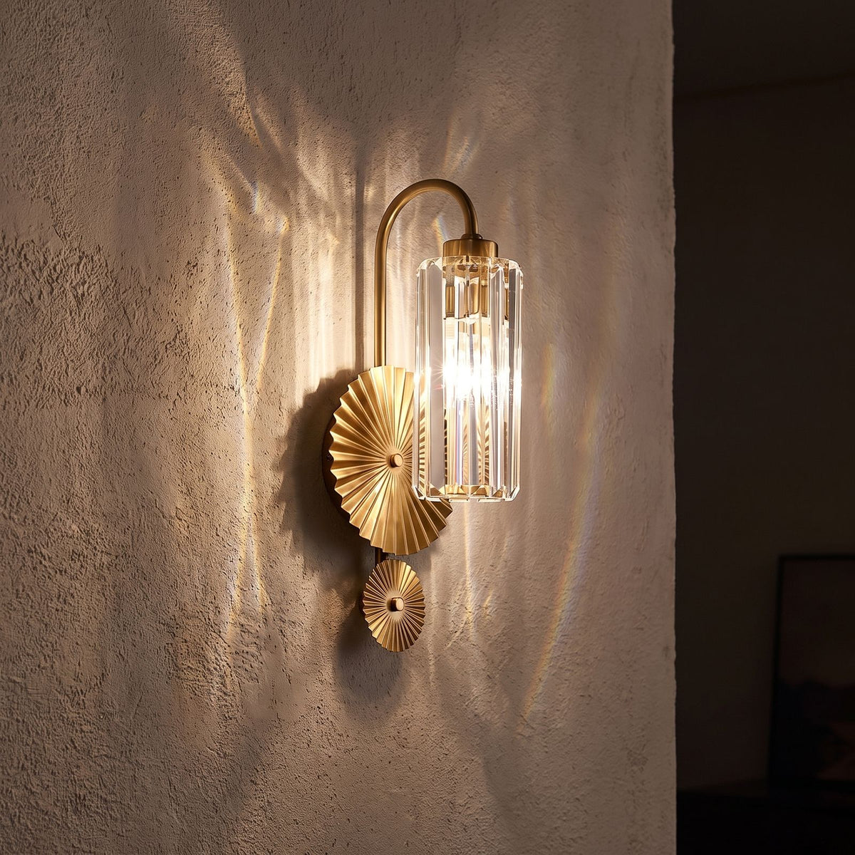 Diagonal Fluted Glass Cylinder Wall Light glowing on a plaster wall at night