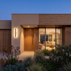Modern home facade at blue hour with a linear LED wall light beside the entry