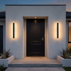 Pair of linear LED wall lights framing a black front door at dusk