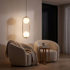 Double glass globe oval hoop pendant light over a reading armchair at night