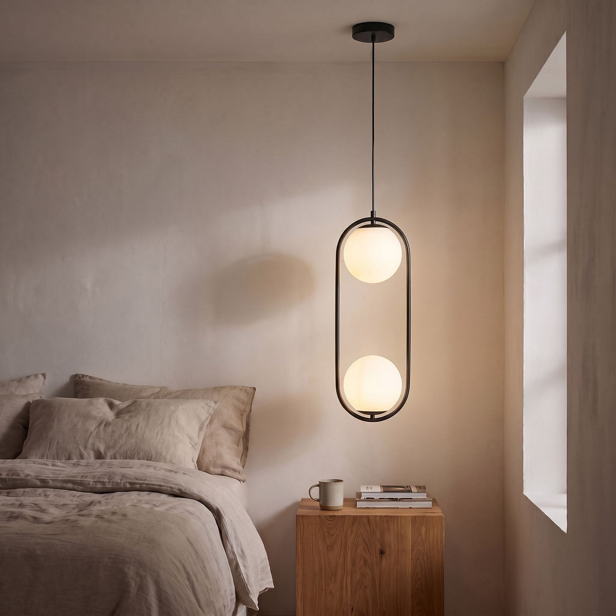 Double Frosted Glass Globe Oval Hoop Pendant Light in black beside a bed