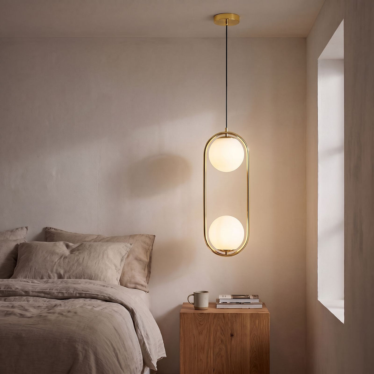 Double Frosted Glass Globe Oval Hoop Pendant Light in gold beside a bed