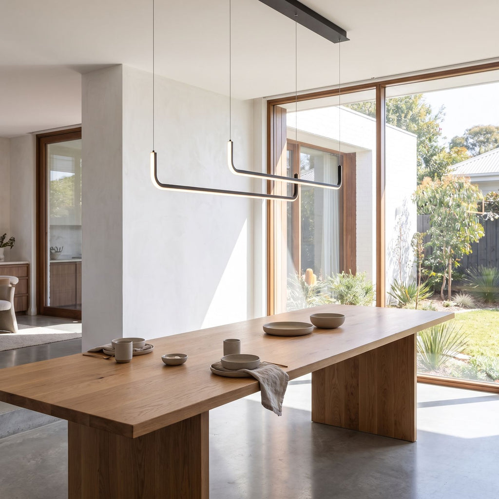 Double U-bar linear LED pendant light above a dining table in daylight