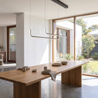 Double U-bar linear LED pendant light above a dining table in daylight