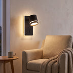 Backlit spotlight bedside wall light above an armchair in a reading corner