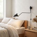 Duckbill Shade Adjustable Arm Wall Light on a bedroom wall beside the bed