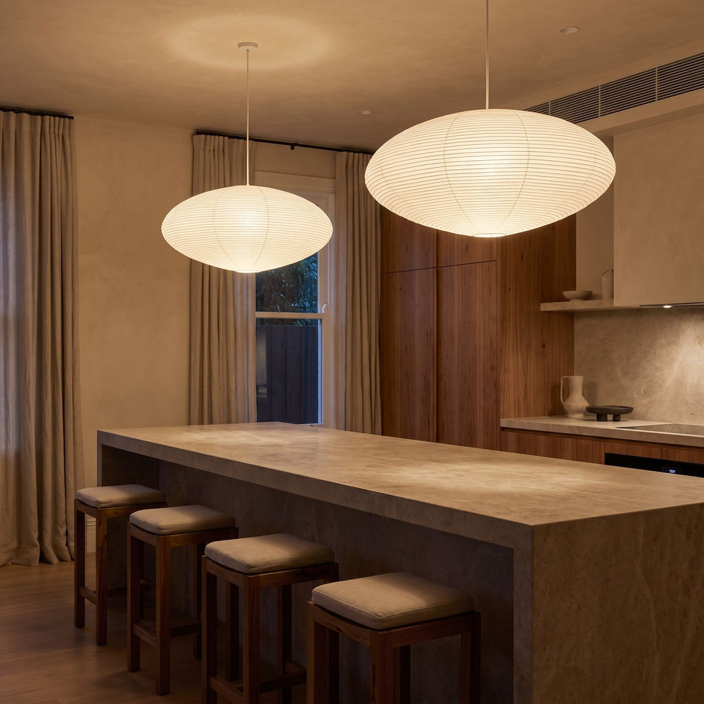 A pair of Faceted Mulberry Paper Pendant Lights over a stone kitchen island