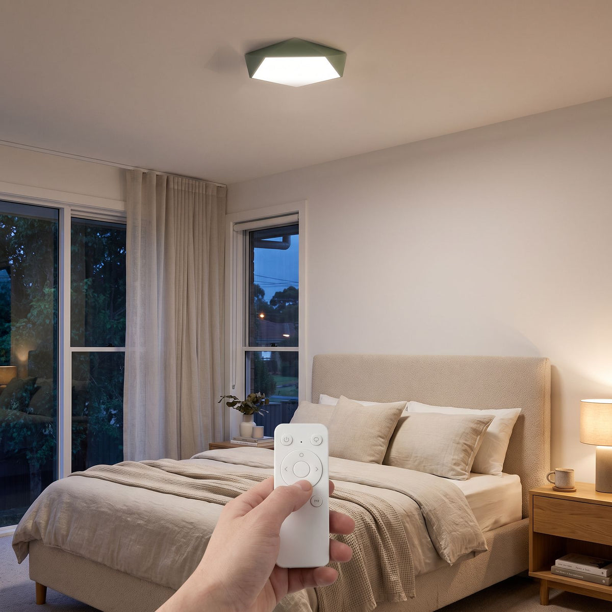 Remote control in hand adjusting the Faceted Pentagon LED Ceiling Light on a bedroom ceiling in the evening