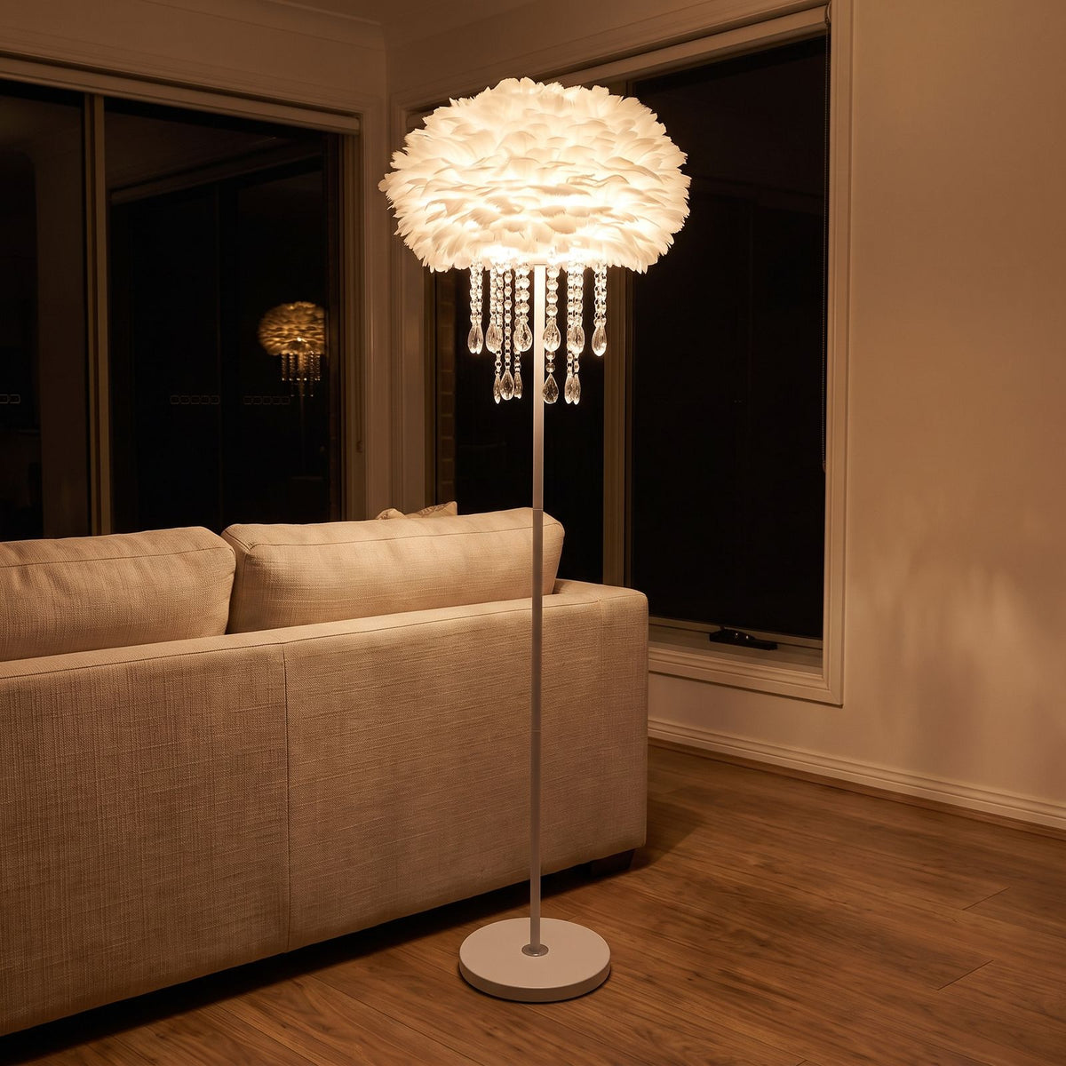 Feather shade crystal drop floor lamp behind a sofa at night