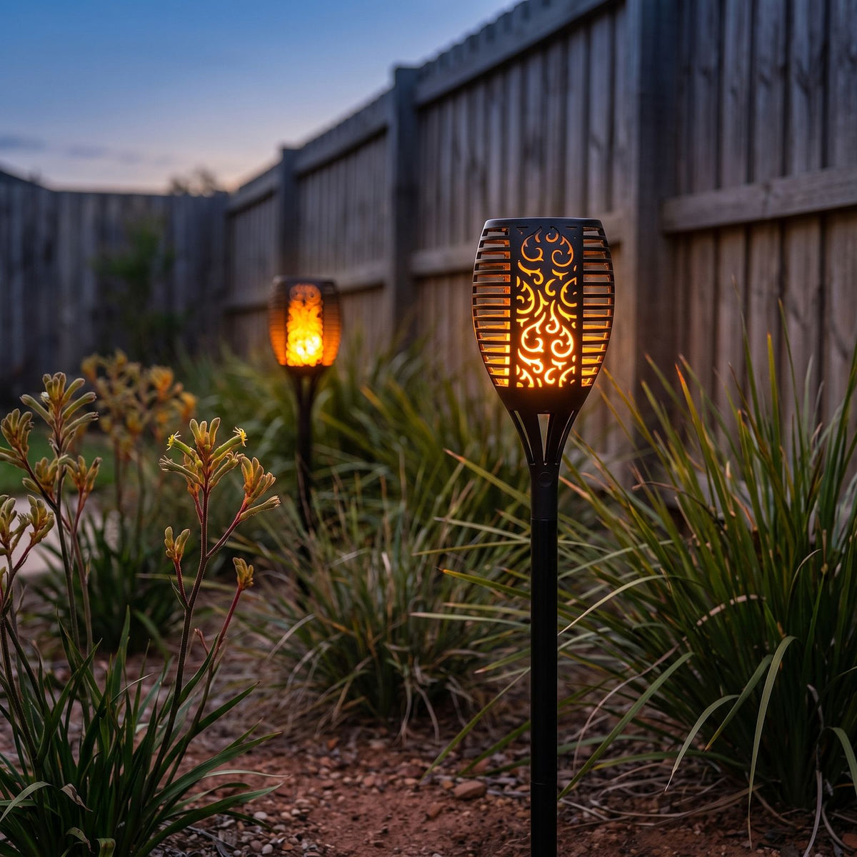 Flame Effect Openwork Torch Solar Garden Light in a garden bed at dusk