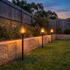 Flame effect solar garden torch along a lawn edge and retaining wall
