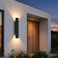 Flat Bar Aluminium Up Down Outdoor Wall Light beside a timber front door at dusk