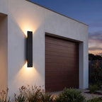 Flat bar up down outdoor wall light beside a garage door at dusk
