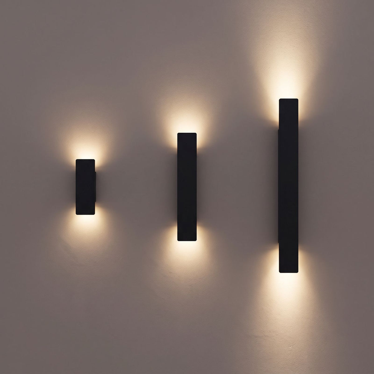 Flat Bar Aluminium Up Down Outdoor Wall Lights in black in the three lengths, 20.5, 41 and 61 cm, side by side on a rendered wall