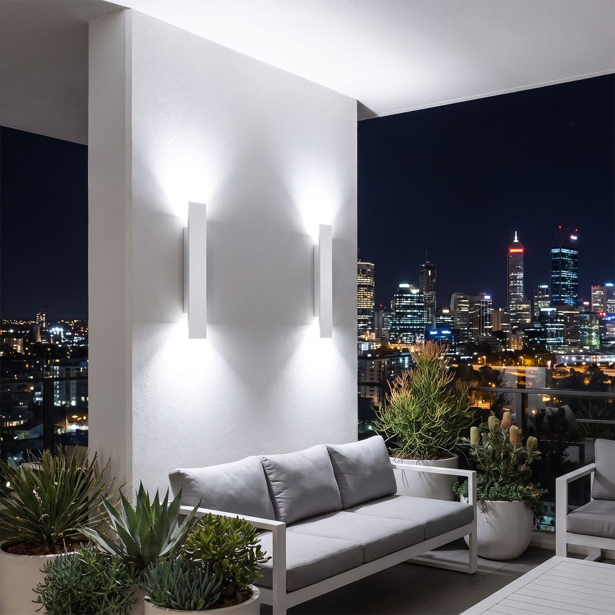 Two Flat Bar Aluminium Up Down Outdoor Wall Lights in white with cool white light on a city apartment terrace at night