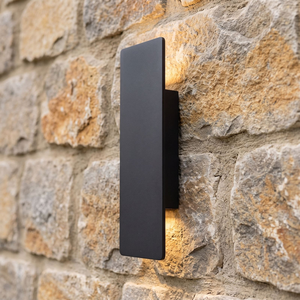 Flat Bar Aluminium Up Down Outdoor Wall Light in black on a natural stone wall, side view of its slim profile