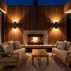 Two Flat Bar Aluminium Up Down Outdoor Wall Lights in black either side of an outdoor fireplace on a timber-clad wall at night