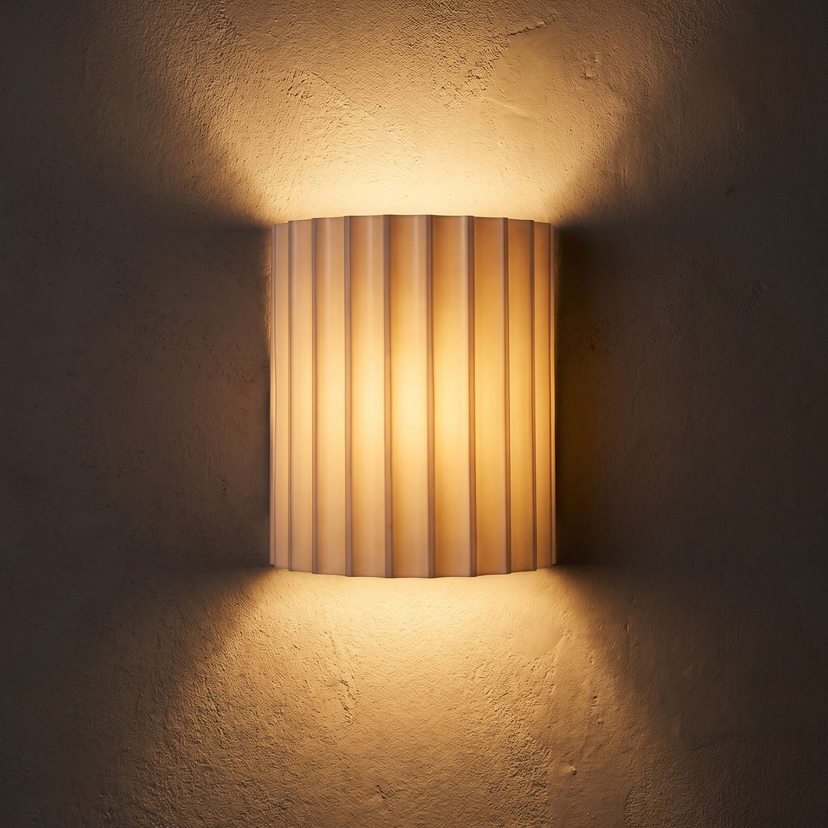 Fluted Resin Wall Light glowing on a plaster wall at night