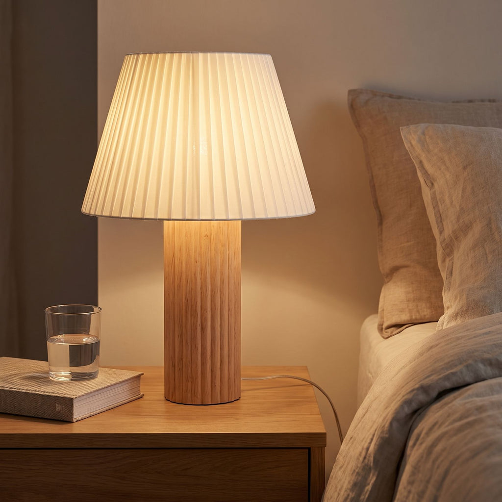 Fluted Wood Column Pleated Shade Table Lamp on a bedside table