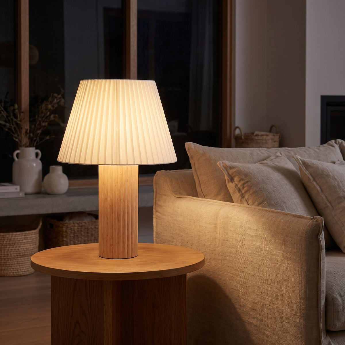 Fluted wood pleated shade table lamp on a side table beside a sofa