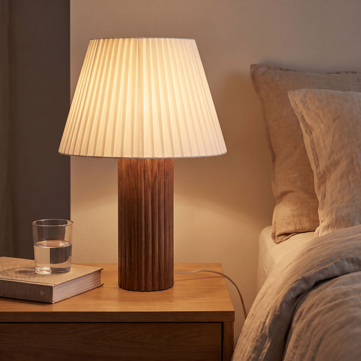 Fluted Wood Column Pleated Shade Table Lamp in walnut on a bedside table