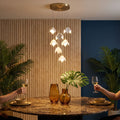 Ceramic Petal Cluster Pendant Light in warm white above a round marble dining table at a dinner party