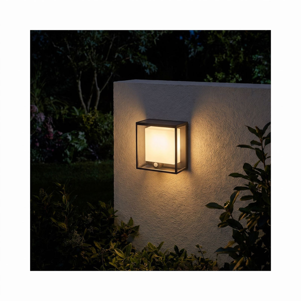 Framed Acrylic Solar Sensor Outdoor Wall Light glowing on a garden wall at night