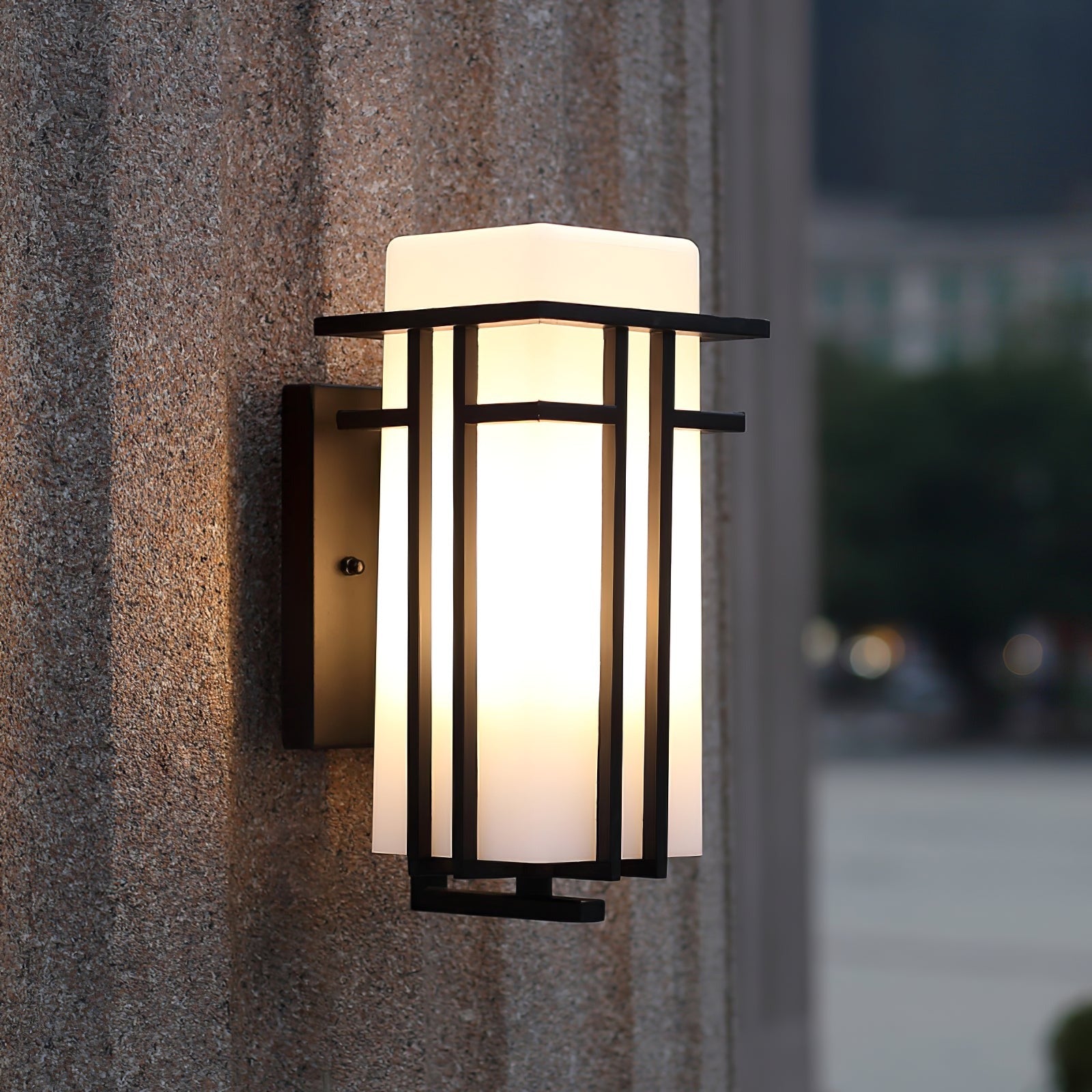 Prairie style wall lantern glowing on a speckled stone wall