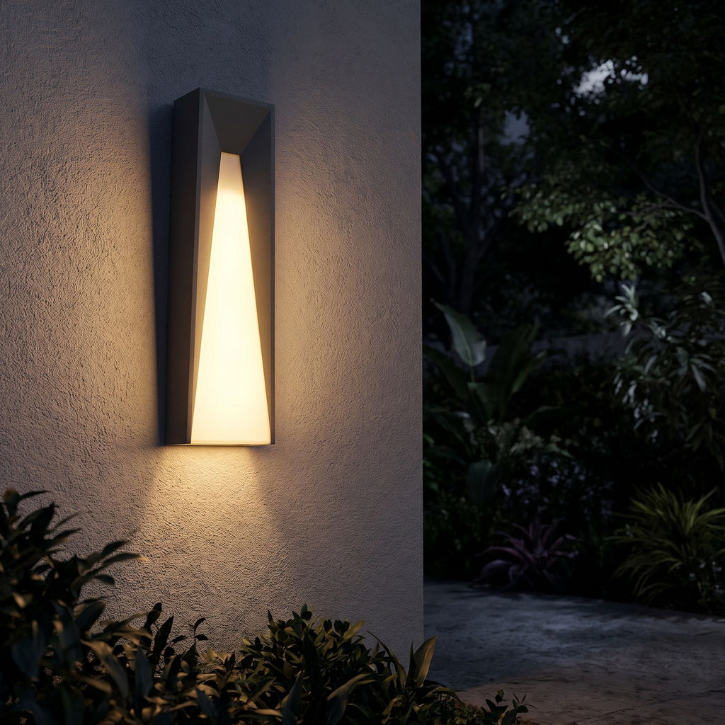 Geometric Layered Metal Outdoor Wall Light glowing on a garden wall at night