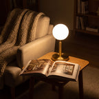 Glass Globe Gold Stem Bedside Table Lamp beside an armchair in a reading corner at night
